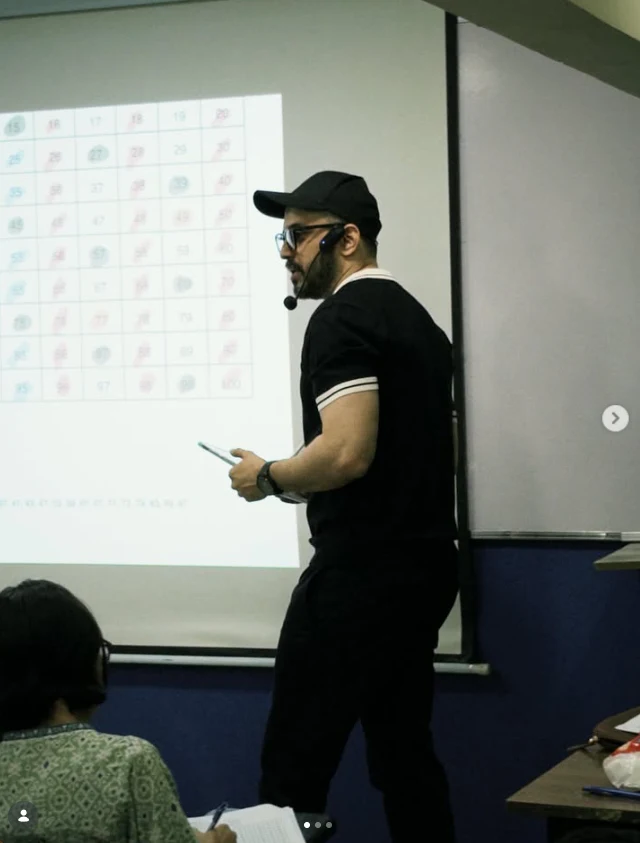 A teacher explaining a lesson beside a projected presentation at The Professionals Core