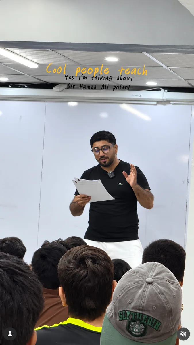 A teacher discussing printed lesson notes with students seated in front of the whiteboard