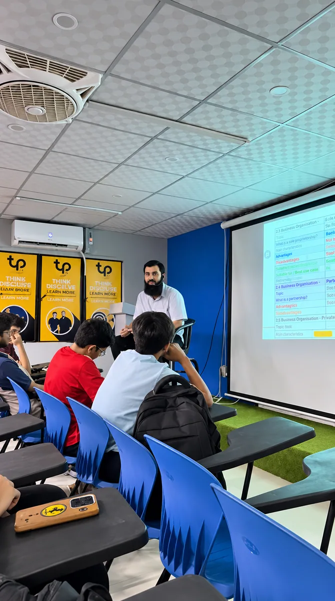 Students attending a business lesson with a projected comparison of business organisations